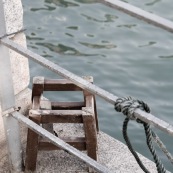 Petit banc en bois décérépi au bord de l'eau avec barrière. Hong-kong.