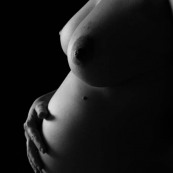 Femme enceinte nue fond noir seins ventre main