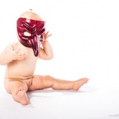 Portrait de bebe avec un masque rouge venitien. Italien. Masque de bal de carnaval. En Guyane.