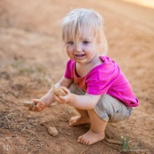 Petite fille en train de jouer avec de la terre et des cailloux. Bebe.