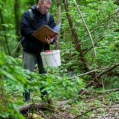 Homme en pleine nature, effectuant un recensement de tritons. Il a des bottes, un seau et un carnet dans lequel il note ses observations. Il est au bord d'une mare. Etude de la variation de population d'amphibiens. Protection des espËces, suivi des populations, dans le cadre d'un contrat Natura 2000.