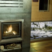 Poele à bois dans un chalet de montagne. Contraste entre le feu et la neige à l'extérieur. Chalet en bois, moderne. En soirée. Chauffage. Insert. Dans les cévennes, mont aigoual.