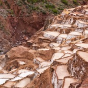 Terrasses des salineras de Maras. Une personne remplie des sacs de sel. Exploitation de sel. L'eau d'une source riche en sel est guidée dans les terrasses, l'eau s'évapore, reste le sel. Balcons. Pérou.