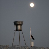 Station meteorologique en montagne avec la lune en arriere plan, paysage lunaire. Pluviometre.