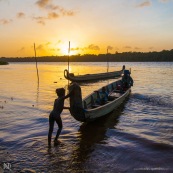 Coucher de soleil en Guyane. Sur le fleuve Maroni. Pirogue et enfants avec leur pere sur la pirogue. Village de Saint Jean du Maroni.