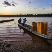 Coucher de soleil en Guyane. Sur le fleuve Maroni. Pirogue transportant du mobilier contemporain DISSI en bois massif de Guyane.