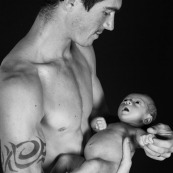 Pére bébé papa dans ses bras fond noir regard