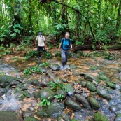 Homm eet femme traversent une rivière en forêt tropicale, bassin amazonien, pérou.