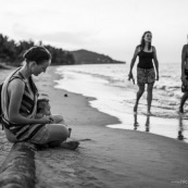 Guyane. Sur la plage des salines (Remire Montjoly) une femme et son bebe en train de regarder le coucher de soleil. Assis sur un tronc de palmier.