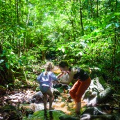 Guyane. Femme et jeune fille enfant en train de se baigner dans une rivière (crique) en pleine foret (sentier du Rorota).  Foret tropicale amazonienne.