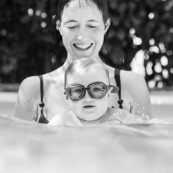 Bebe dans une piscine avec sa maman. En train d'apprendre a nager. Avec des lunettes de piscine.