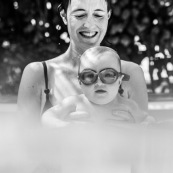 Bebe dans une piscine avec sa maman. En train d'apprendre a nager. Avec des lunettes de piscine.