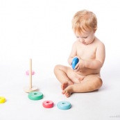 Bebe petite fille en train de jouer avec un jeu en bois. Anneaux a passer sur une tige. jeu d'adresse. Habilete. Jouet. Ronds perces.