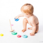 Bebe petite fille en train de jouer avec un jeu en bois. Anneaux a passer sur une tige. jeu d'adresse. Habilete. Jouet. Ronds perces.