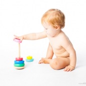 Bebe petite fille en train de jouer avec un jeu en bois. Anneaux a passer sur une tige. jeu d'adresse. Habilete. Jouet. Ronds perces.