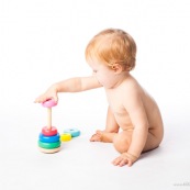 Bebe petite fille en train de jouer avec un jeu en bois. Anneaux a passer sur une tige. jeu d'adresse. Habilete. Jouet. Ronds perces.