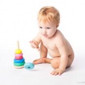 Bebe petite fille en train de jouer avec un jeu en bois. Anneaux a passer sur une tige. jeu d'adresse. Habilete. Jouet. Ronds perces.