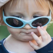 Bebe petite fille enfant. Reflet dans ses lunettes de sa main avec du pain. En train de manger.