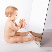 Portrait de bebe avec un miroir. Il se regarde dans la glace.