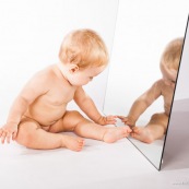 Portrait de bebe avec un miroir. Il se regarde dans la glace.