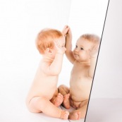 Portrait de bebe avec un miroir. Il se regarde dans la glace.