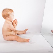 Portrait de bebe avec un miroir. Il se regarde dans la glace.