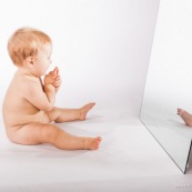 Portrait de bebe avec un miroir. Il se regarde dans la glace.