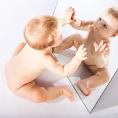 Portrait de bebe avec un miroir. Il se regarde dans la glace.