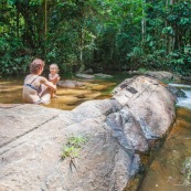 Baignade a Saul en foret tropicale amazonienne. Riviere. Crique. Sentier Roche bateau. En famille. Avec des enfants et bebe. Bain dans une crique sablonneuse.  Maman et sa fille. Tourisme.  Parc amazonien de Guyane.
