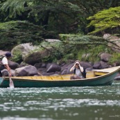 Femme sur une pirogue en train de regarder avec des jumelles.