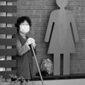 A hong-kong en Chine, femme devant les toilettes en train d'attendre pour faire le menage.